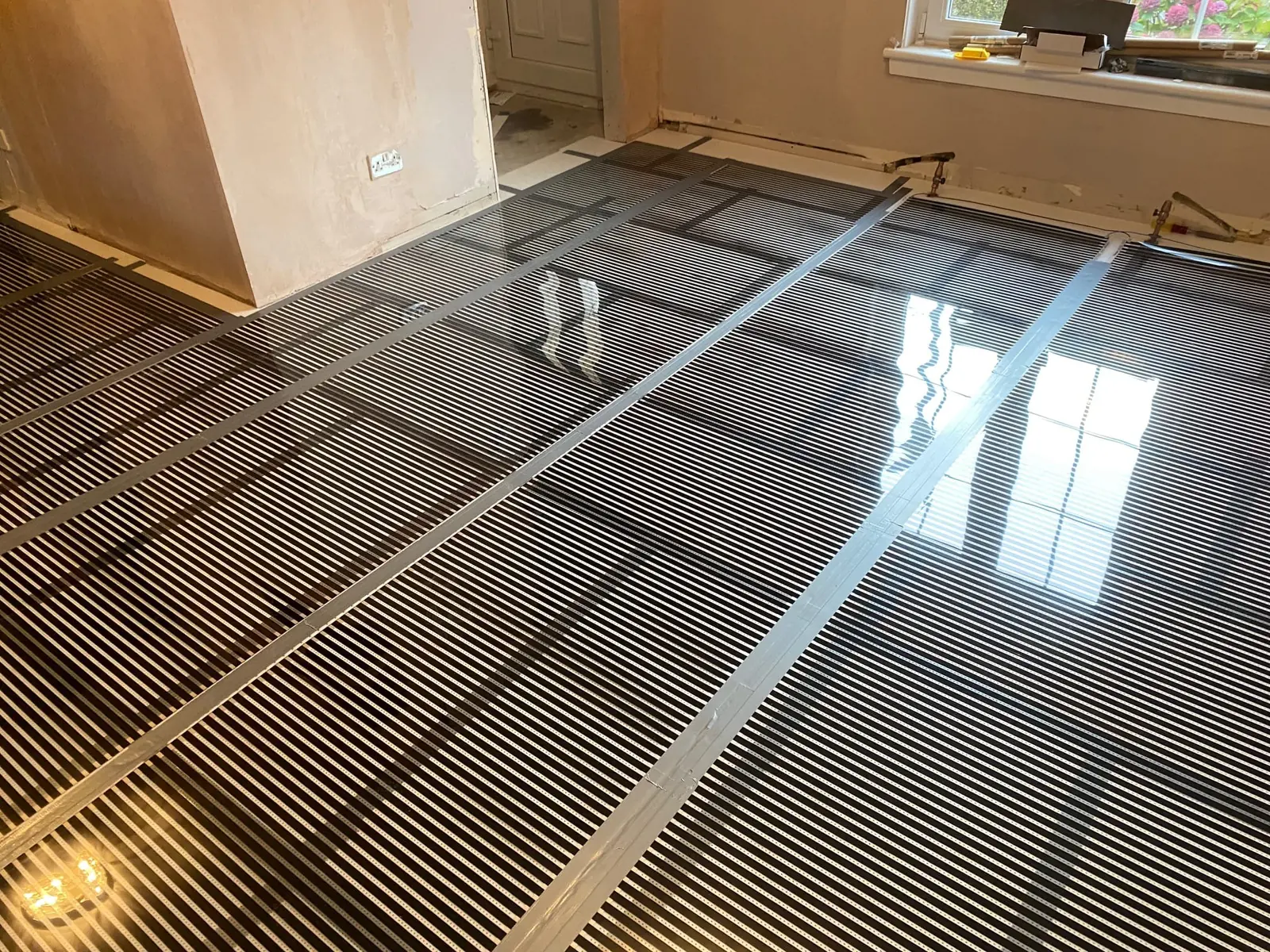 Carbon heating film laid across a floor ahead of a wood finish
