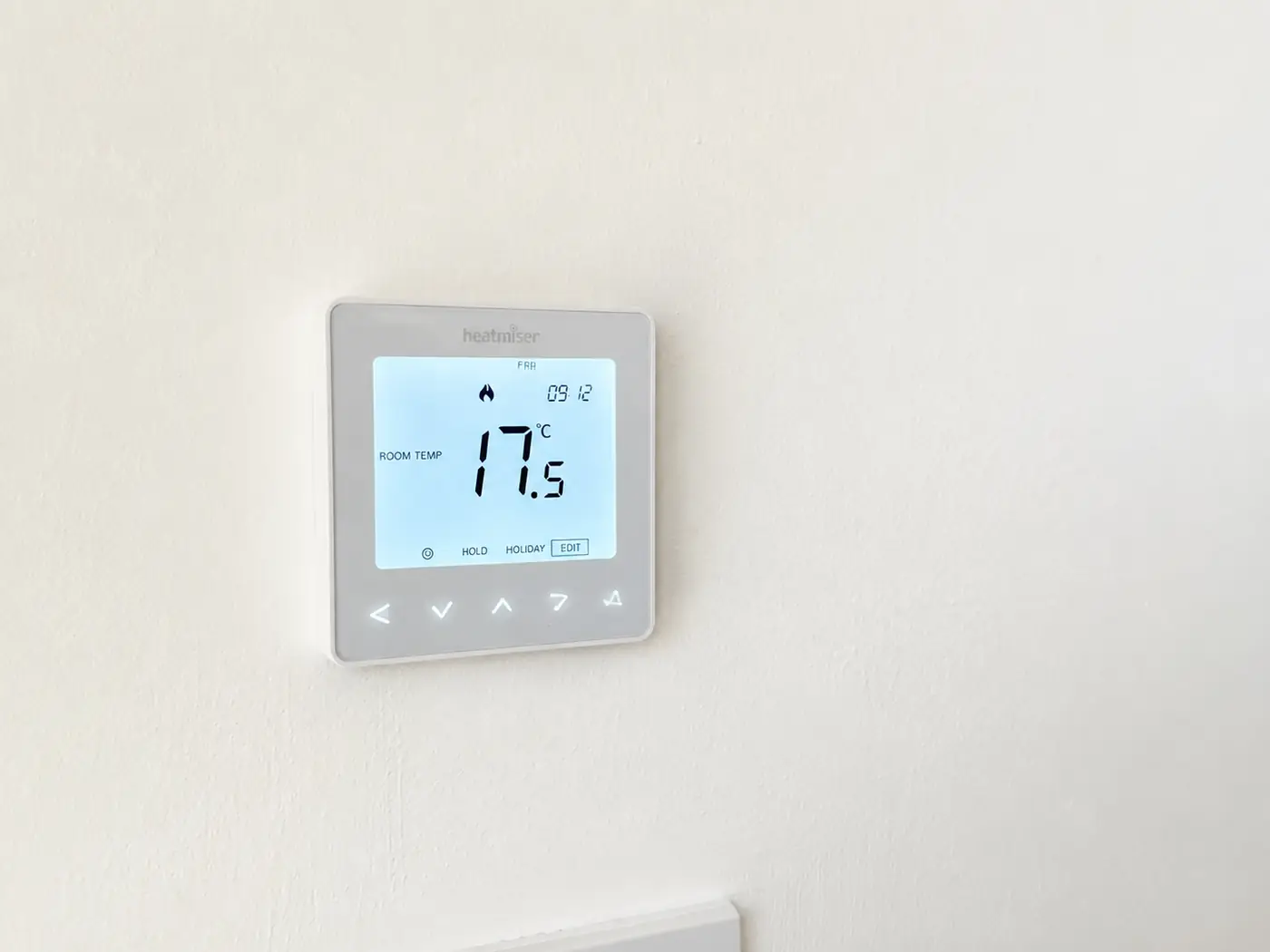Touch thermostat mounted on a wall showing the colour display